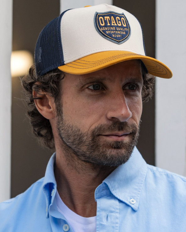 le modèle porte une Casquette Qualicap Otago rugby écru ocre et marine