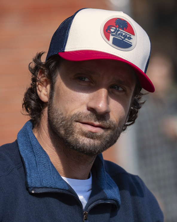 le modèle porte une Casquette Silcap Otago rugby écru rouge marine