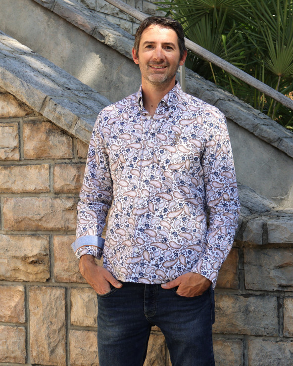 le modèle porte une Chemise manches longues pour homme 294 Otago blanche à motifs bleu marine et marron