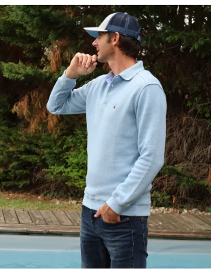 le modèle porte un Polo bleu pastel manches longues pour homme 25POML1 Otago rugby vert ou sweat bleu pastel col polo