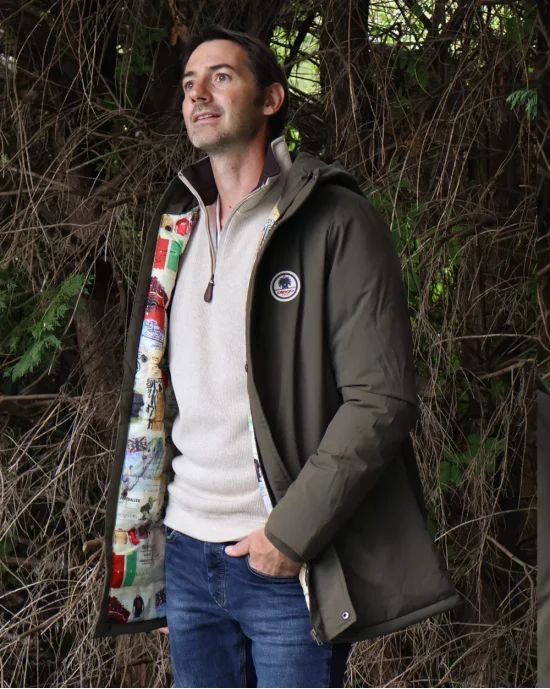 le modèle porte une Doudoune longue kaki déperlante pour homme Lamyan Otago rugby avec capuche avec un sweat col zip écru