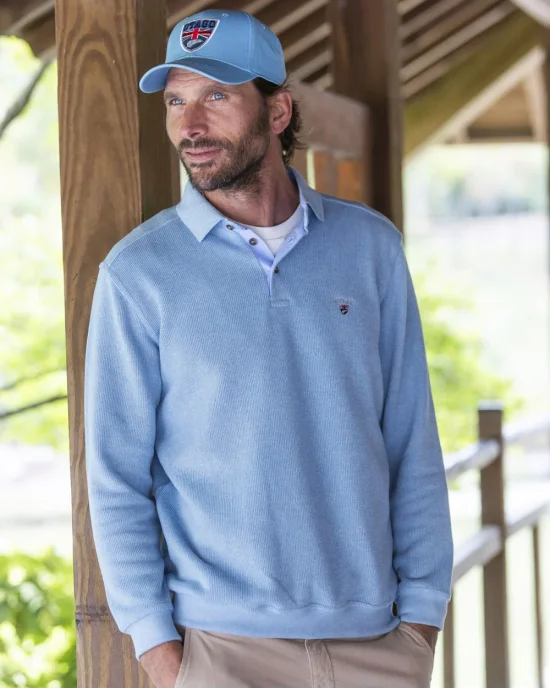 le modèle porte un Polo bleu pastel manches longues pour homme 25POML1 Otago rugby ou sweat bleu pastel col polo
